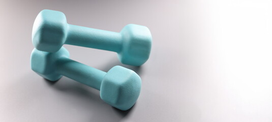 Close-up of blue dumbbells on grey background, planning weight loss, equipment for sport activity. Sport, health, physical activity, habit concept