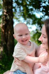 Happy mother and child hugging in summer park with love, smile and care or health development. Happy family concept. Portrait of human emotions. Advertising of children's products. Vertical image