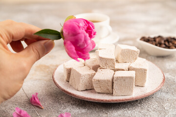 Coffee marshmallow with cup of coffee with hand on brown concrete. side view, selective focus