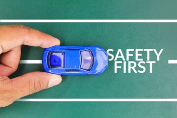 hand holding the car with the words SAFETY FIRST, to remind the driver to drive carefully and avoid...