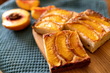 A dessert made of sliced peaches is on a wooden cutting board. The dessert is covered in sugar and looks delicious.