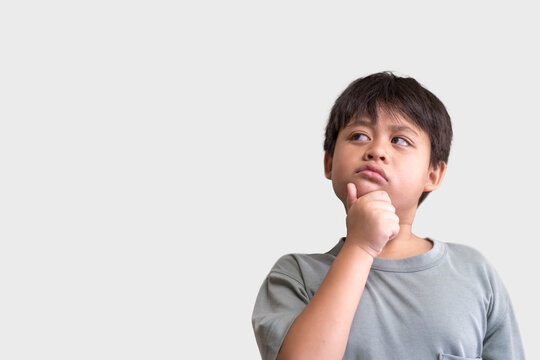 Young asian boy with contemplative expression thinking pose looks upward as if pondering a question or idea, learning and thought process of children, education, learning, childhood and inspiration