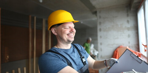 Portrait of smiling builder holding clipboard and writing down needed work material for renovation....