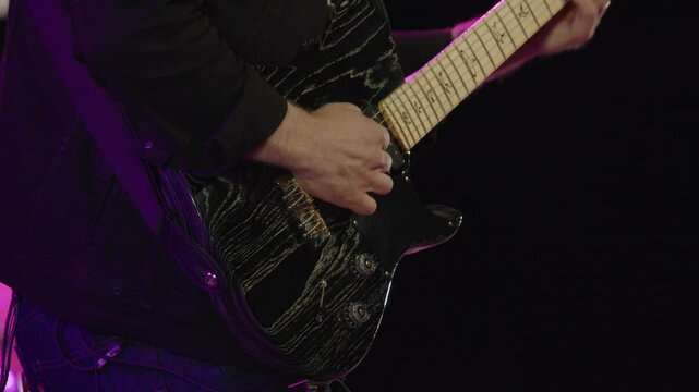 Musician plays beautiful electric guitar on stage during performance