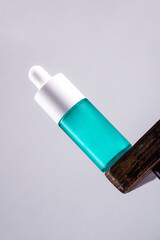 Blue glass cosmetic bottle, Skin care or sunscreen cosmetic with stylish props on grey background.