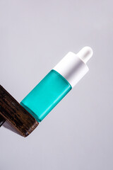 Blue glass cosmetic bottle, Skin care or sunscreen cosmetic with stylish props on grey background.