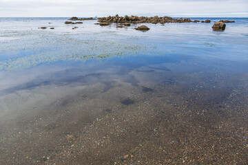 Rocks in the sea with a blue sky and clouds in the background