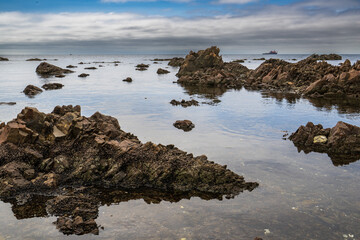 Rocks in the sea with a blue sky and clouds in the background