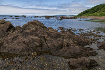 Rocks in the sea with a blue sky and clouds in the background