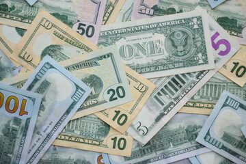 Big amount of US dollar bills in different nominations on table. Many dollar banknotes under natural light