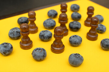 Black wooden chess pawns and blueberry