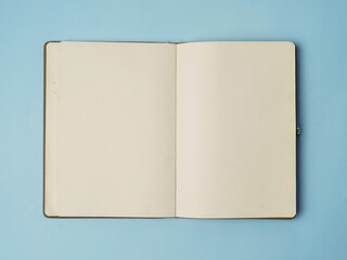 Open empty white paper book laying on blue desk, top view flat lay