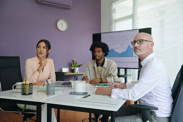 Group of marketing specialists sitting at presentation in board room