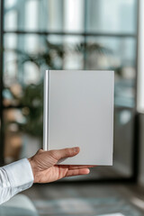 A businessman's hand holds a white book blank without text. Mockup for advertising