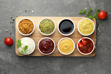 Many different sauces and spices on grey table, flat lay