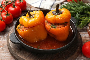 Tasty stuffed peppers in pan and products on wooden rustic table, closeup