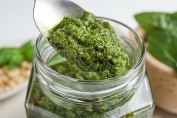 Taking tasty pesto sauce at table, closeup