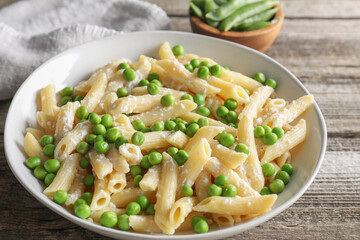 Delicious pasta with green peas and cheese on wooden table, closeup