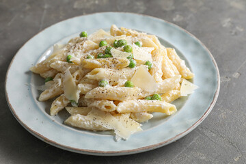 Delicious pasta with green peas, cheese and creamy sauce on grey table