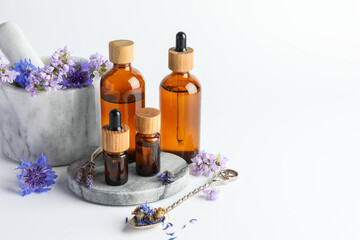 Aromatherapy. Different essential oils, flowers, mortar and pestle on white background, space for text