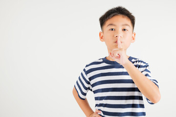 Young kid boy making finger on lips mouth silent quiet gesture, Happy Asian primary child marking silence for stop quiet, mute studio shot isolated on white background with copy space © sorapop