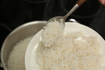 Taking boiled rice from pot into plate, closeup
