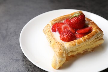 Tasty puff pastry with strawberries on grey table, closeup