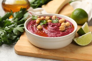 Tasty beet hummus with chickpeas and parsley in bowl on light table