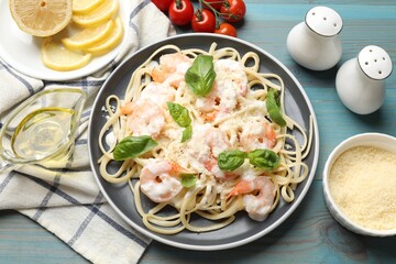 Tasty pasta with shrimps on light blue wooden table, flat lay