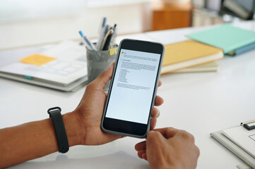 Close-up of marketer reading information in vlm model on smartphone while working in office