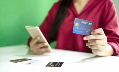 Asian girl shopping online holding credit and using smartphone enter their card number in the mobile phone app to purchase and payment in internet store