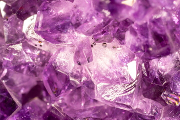 Amethyst purple crystals. Gems. Mineral crystals in the natural environment. Texture of precious and semiprecious stones. Seamless background with copy space colored shiny surface of precious stones.