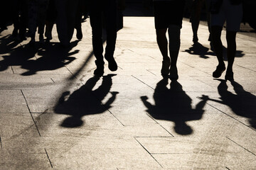 Black silhouettes and shadows of people on the street. Crowd walking down on sidewalk, concept of pedestrians, crime, society, city life