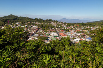 Obraz premium Scenic view of Concepcion de Ataco, a historic colonial village on the Flowers Route (Ruta de Las Flores) in the mountains of El Salvador. Wide angle, from the cross viewpoint (Mirador de La Cruz).