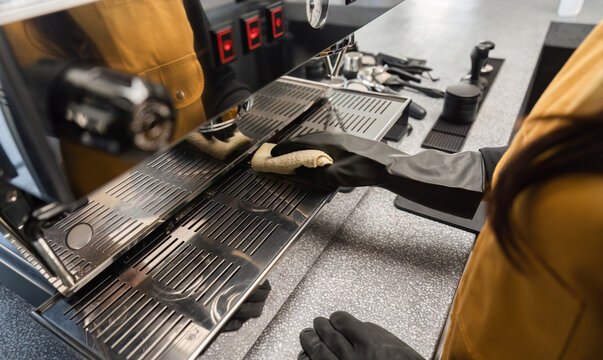 Coffee Shop Cleaning Staff Maintaining Espresso Machine in Modern Cafe Environment