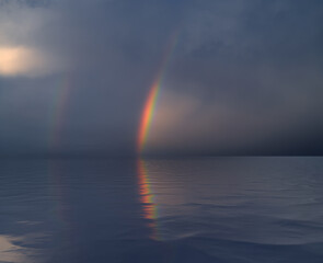 Rainbow reflecting in water surface.