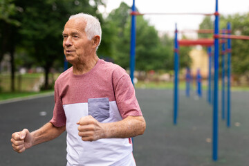 Obraz premium Old man running beside outdoor sports ground