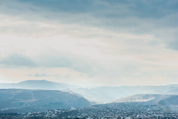 View of the Georgian city of Tbilisi from the side of the sculptural composition Chronicle of Georgia. Aerial view of houses and mountains in Tbilisi, Georgia.