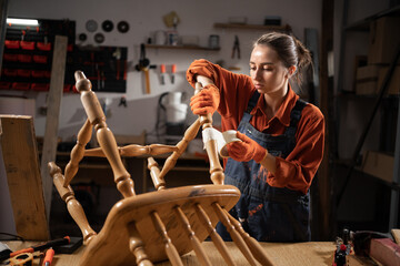 repair, diy and furniture restoration concept. Young attractive woman sticking adhesive tape to old wooden chair for repainting and restore it