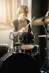 Fototapeta premium Young drummer playing drums in music studio, vibrant and energetic atmosphere, vertical 