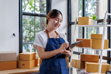 Startup SME small business entrepreneur of freelance Asian woman wearing apron using laptop and box...