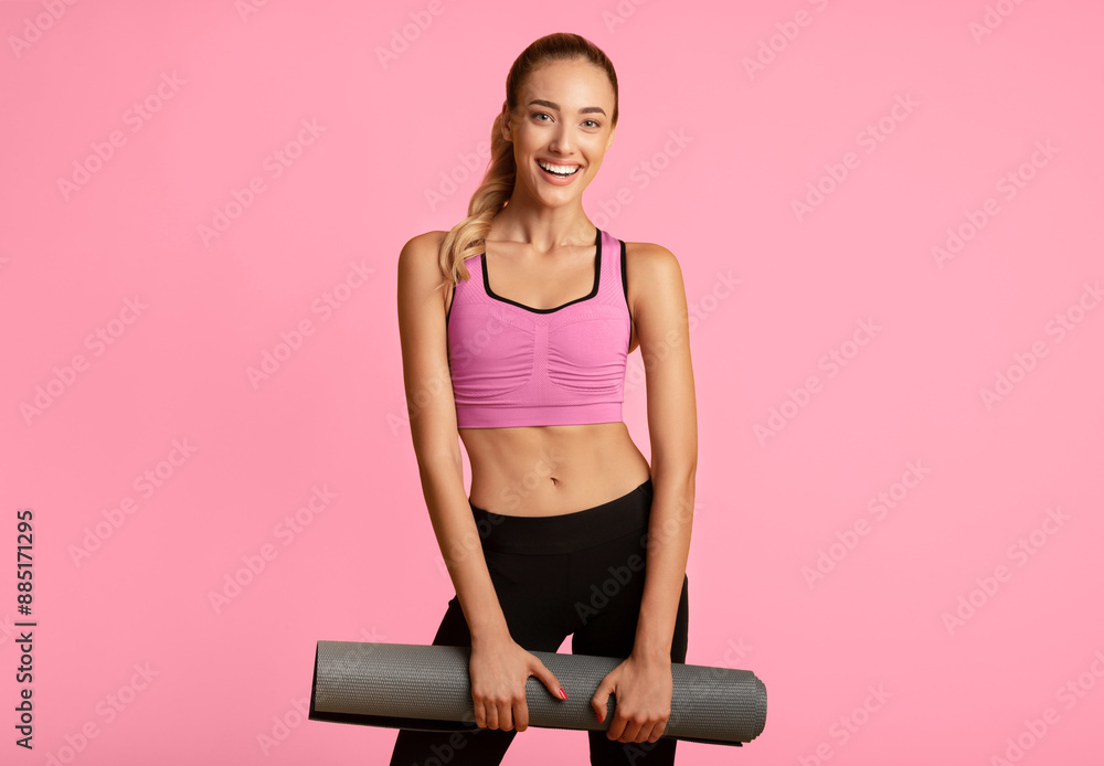 Wall mural Fitness Concept. Young Woman Holding Gym Mat Smiling At Camera On Yellow Studio Background.