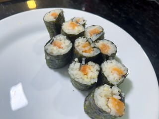 Delicious salmon sushi rolls on a white plate, fresh ingredients, perfect bites ready to be enjoyed