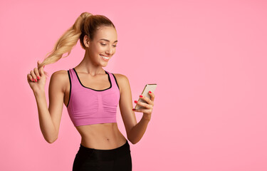 Fitness Apps. Slim Girl Using Smartphone During Workout On Yellow Studio Background. Copy Space