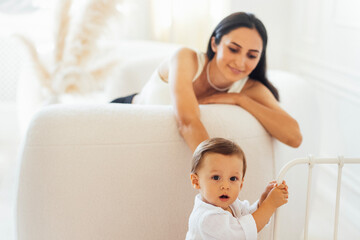 Young smiling woman is having fun with her little baby at home.
