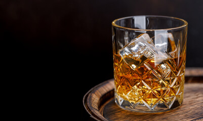 Whiskey glass with ice on a rustic barrel, a classic sip