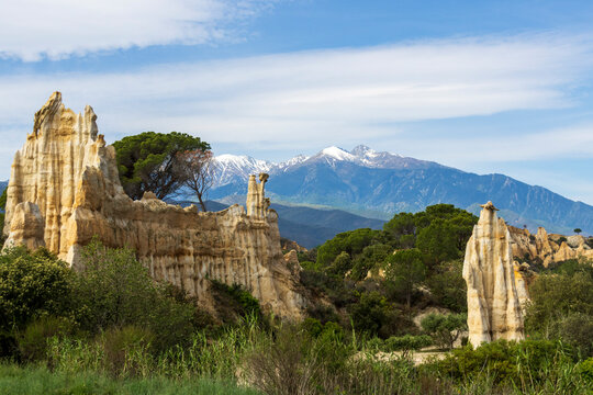 Eroded sandstone cliffs called Orgues de l'Ille sur Tet, with snow-capped Mount Canigou in the background.