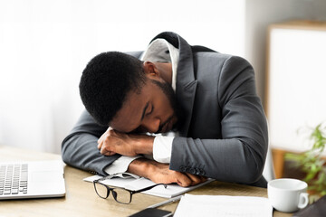 Fototapeta premium Sleep at work. Tired, overworking african american businessman napping in modern white office interior, panorama with copy space