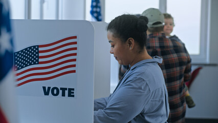 Multi cultural American citizens come to voting booth in polling station office. National Election...