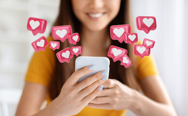 A close-up photo of a young woman smiling as she uses her smartphone. Surrounding her are numerous...